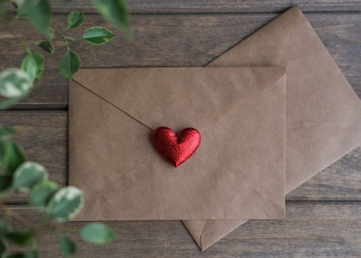 Brown envelope with red heart chocolate on seal