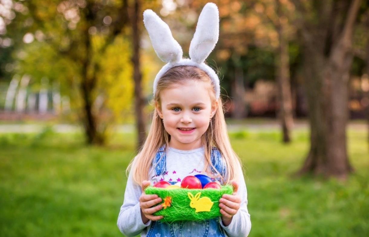 Child wearing bunny ears carrying easter basket